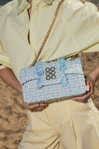 Person holding a blue floral clutch bag with a textured surface.