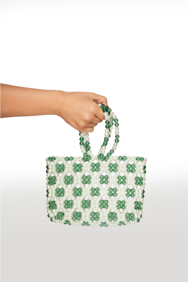 Hand holding a green and white checkered handbag against a white background