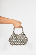 Hand holding a silver woven handbag against a white background