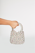 Hand holding a beaded handbag against a white background