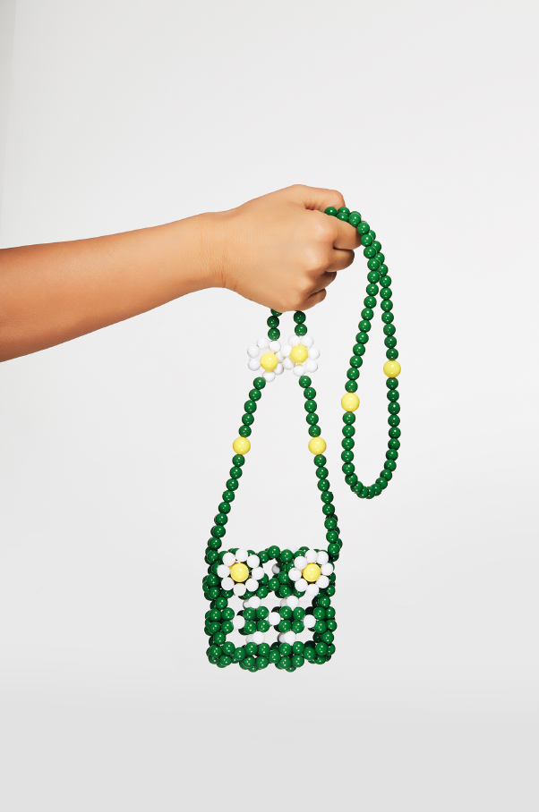 Hand holding a green beaded bag with floral design on a white background