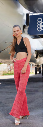 Woman in black top and red pants standing in front of an Audi airplane.
