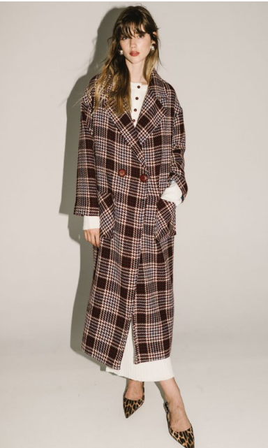 Woman wearing a plaid coat against a plain background