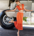 Woman in an orange dress standing next to a vintage airplane