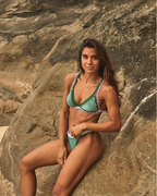 Woman in a green bikini sitting on a rock with a natural background
