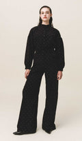 A person standing wearing black carduroy pants with Stone embellishments and a wide-leg, mid-rise fit.