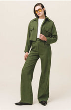 A woman wearing a green button-up crop jacket with large flap pockets and a white top.
