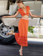 Woman in an orange dress standing next to a vintage vehicle