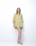 Woman wearing a yellow striped shirt dress on a white background