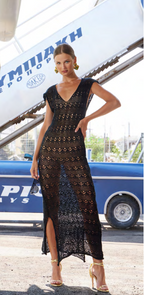 Woman in a black lace dress standing in front of a boat with 'Ymniak' branding.