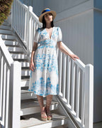 Woman in a blue and white dress standing on white stairs