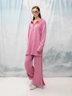 Woman wearing a pink outfit with sunglasses against a light background