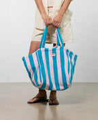 Person holding a striped beach bag with a plain background