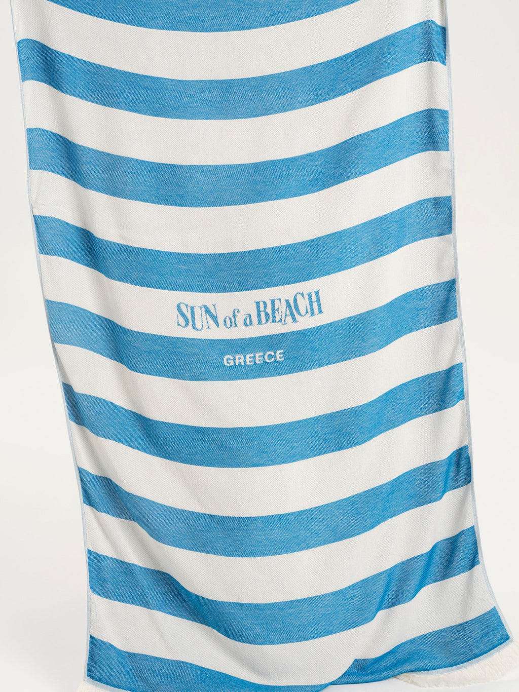 Blue and white striped towel with 'Sun of a Beach Greece' text on a white background