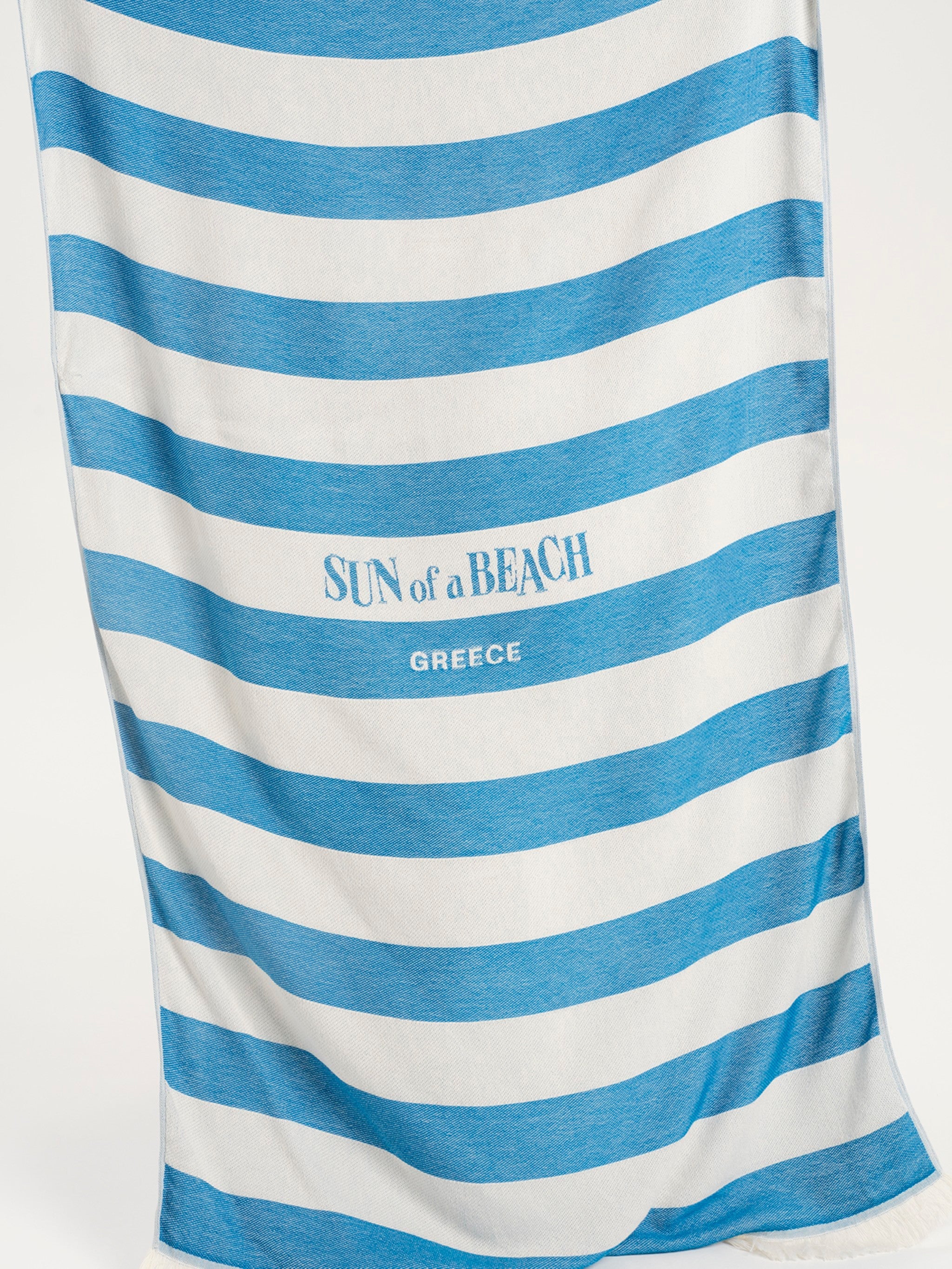 Blue and white striped towel with 'Sun of a Beach Greece' text on a white background
