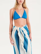 Woman wearing a blue bikini top and striped sarong on a white background