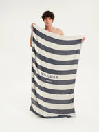 Man holding a striped towel with 'Sun of a Beach' branding on a white background