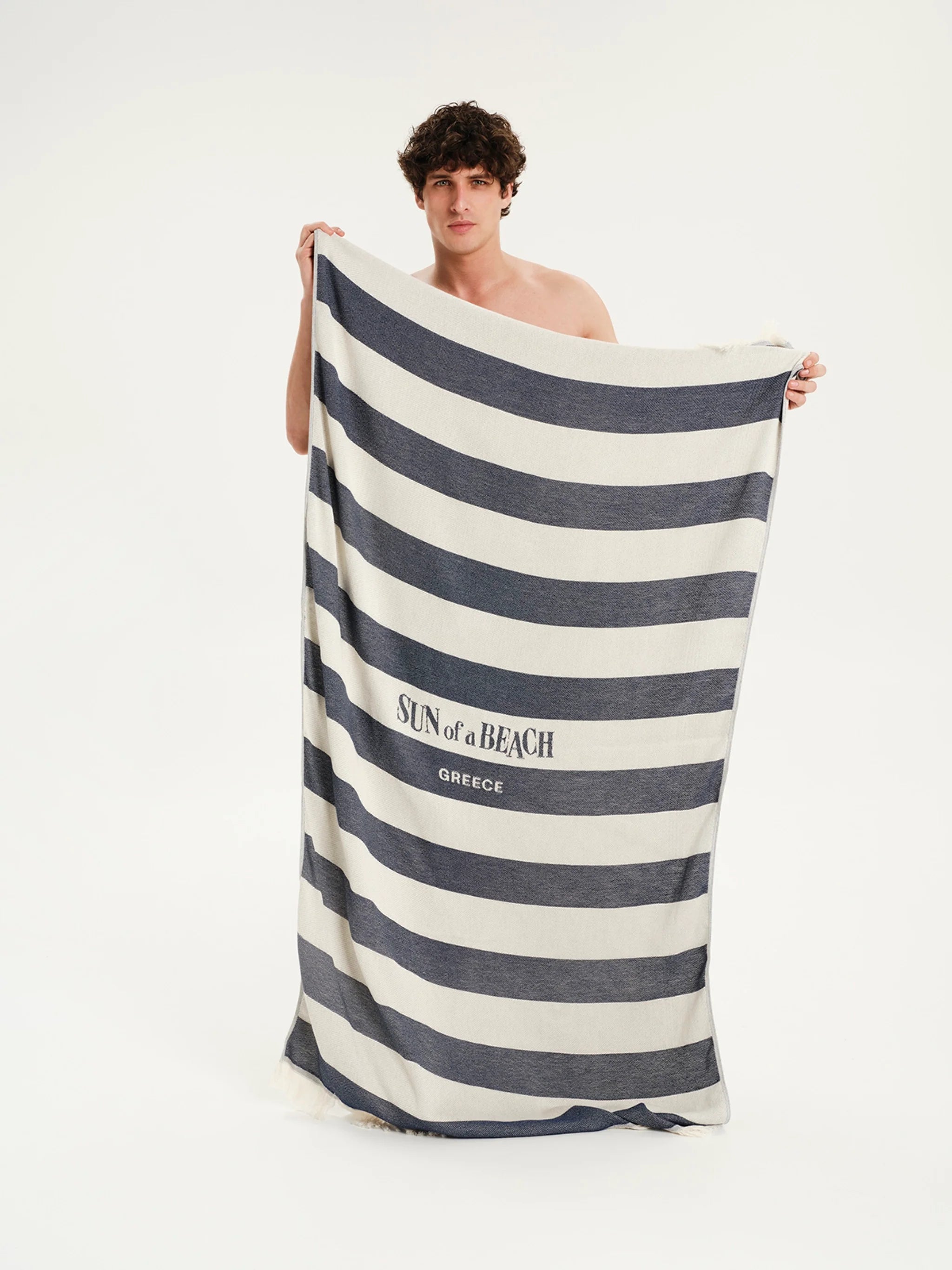 Man holding a striped towel with 'Sun of a Beach' branding on a white background