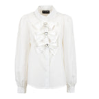 An off-white long-sleeve blouse with a high collar, buttoned front, and three large decorative bow details on the chest, each accented with a small rhinestone. The brand label on the collar reads 'L'EAU D'INCH'.