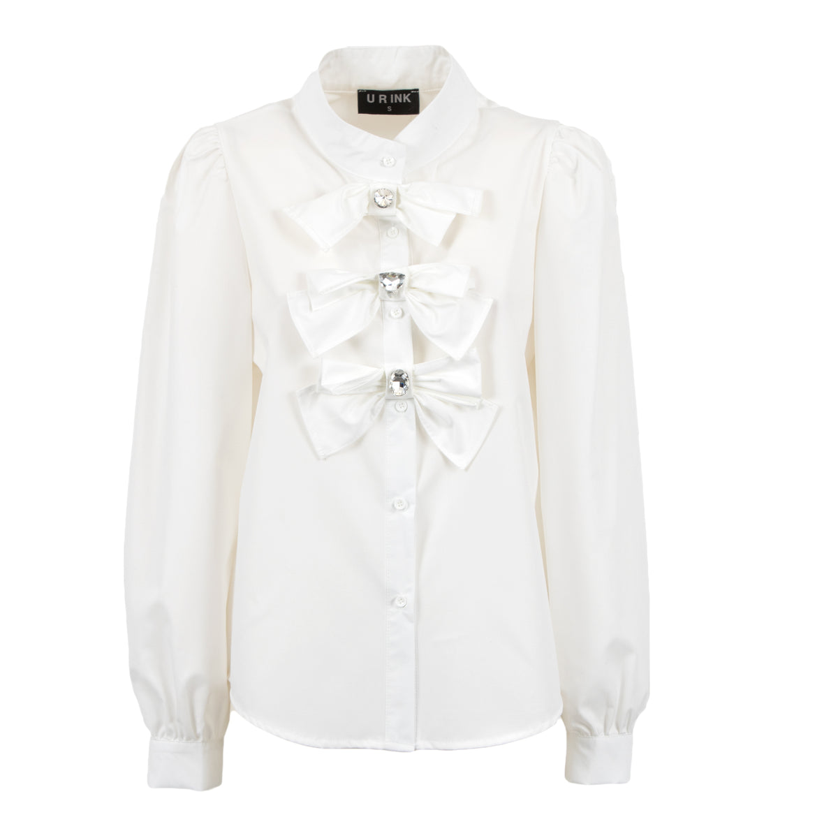 An off-white long-sleeve blouse with a high collar, buttoned front, and three large decorative bow details on the chest, each accented with a small rhinestone. The brand label on the collar reads 'L'EAU D'INCH'.