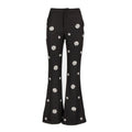 Black flared pants with white embroidered daisy patterns, shown against a plain white background.