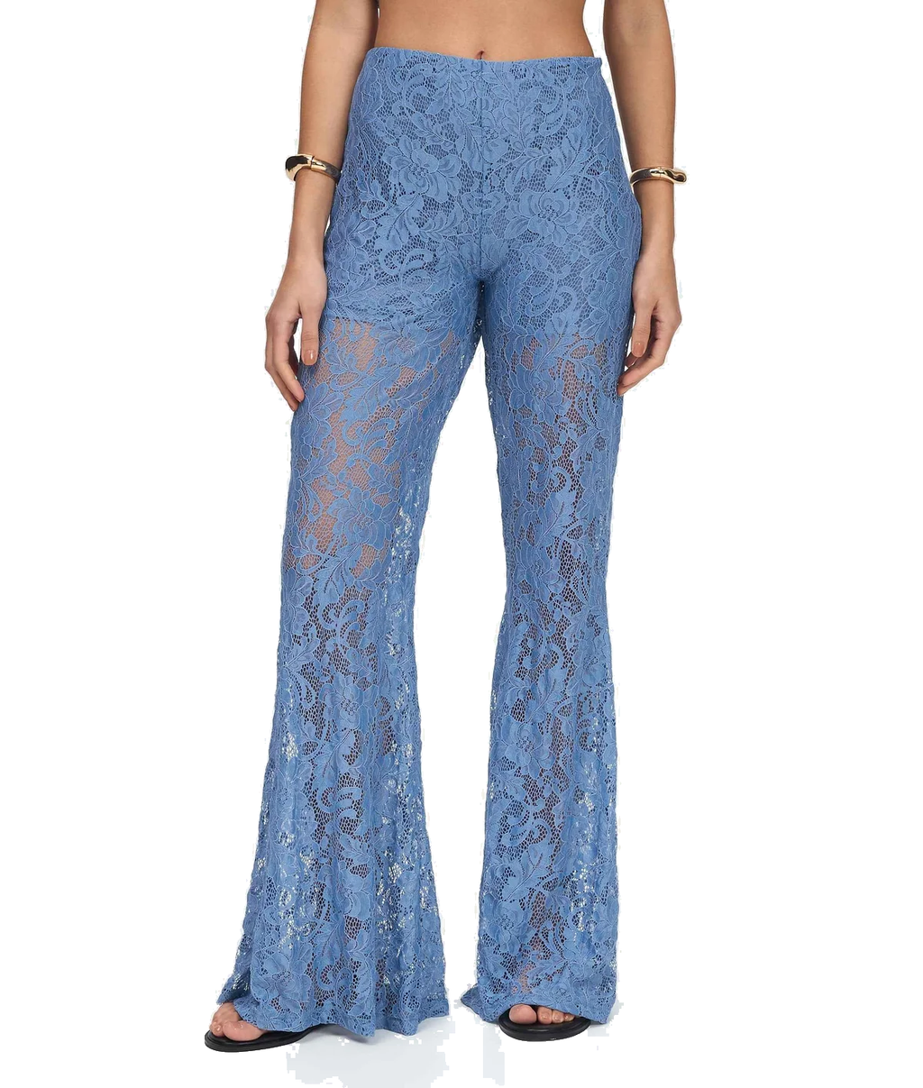 A model is shown from the waist down wearing high-waisted, wide-leg blue lace pants with a sheer floral pattern, paired with black sandals and gold bracelets, against a plain white background.
