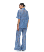A woman shown from the back wearing a matching blue lace short-sleeve top and wide-leg pants set, photographed against a plain white studio background.