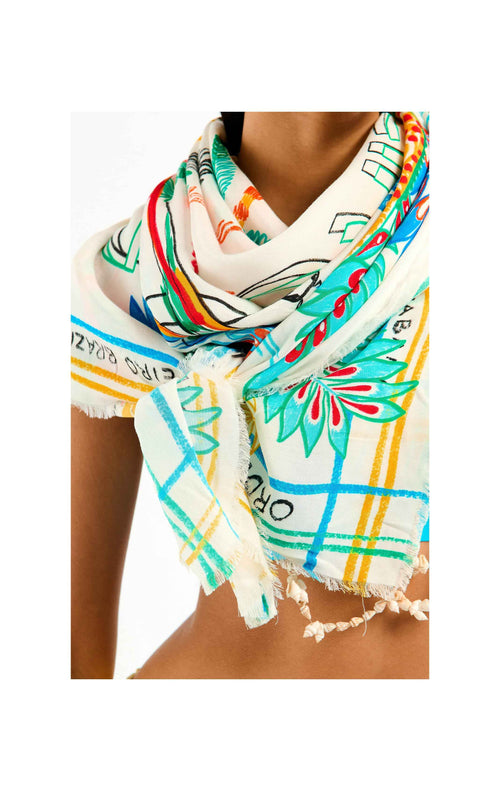 Colorful scarf with tropical patterns worn by a person on a white background