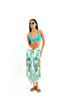 Woman wearing a blue bikini top and colorful sarong on a white background