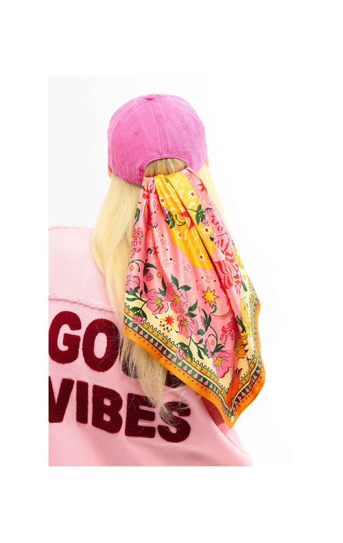 Person wearing a pink cap and colorful scarf with 'Good Vibes' text on a white background