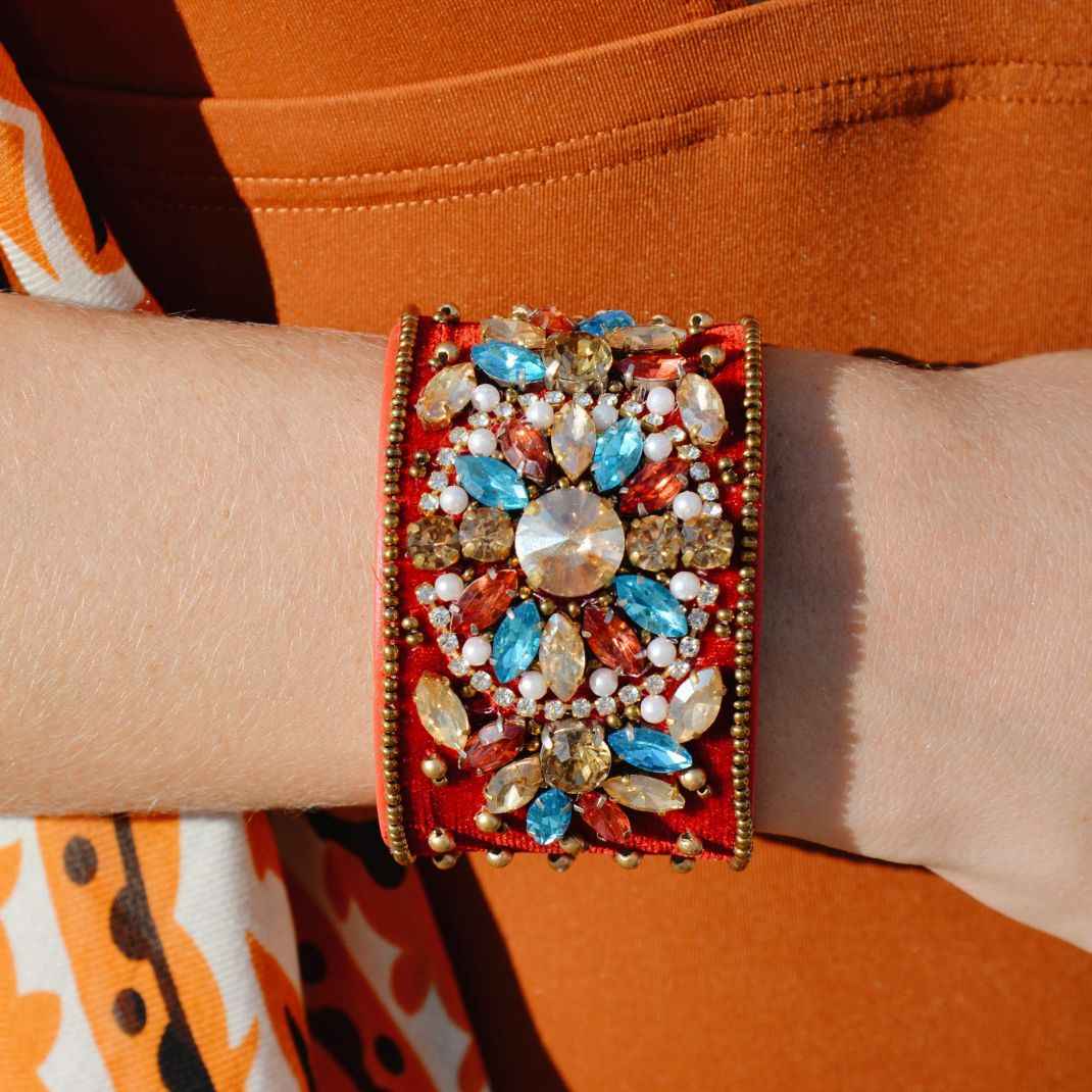 Beaded bracelet with multicolored stones on a wrist against an orange background