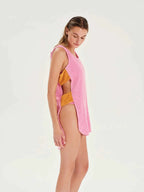 Woman wearing a pink cover-up over a yellow bikini on a white background