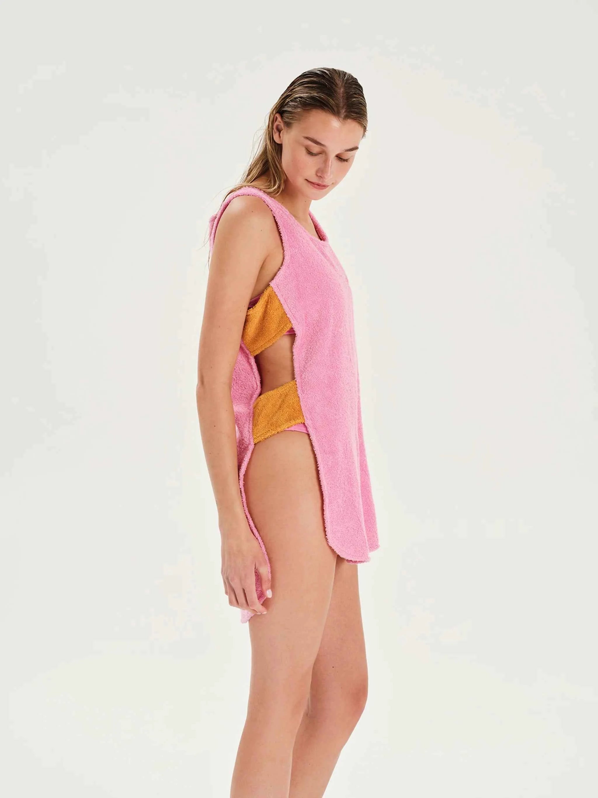 Woman wearing a pink cover-up over a yellow bikini on a white background