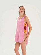 Woman wearing a pink sleeveless dress with a colorful pattern on a white background