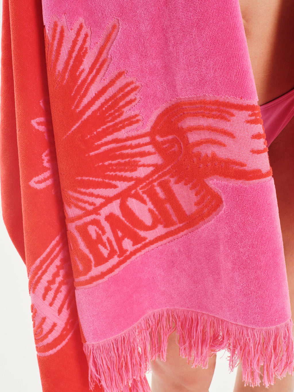Pink towel with 'Beach' and palm tree design, held by a person.