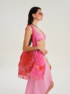 Woman wearing a pink outfit with a matching bag on a white background