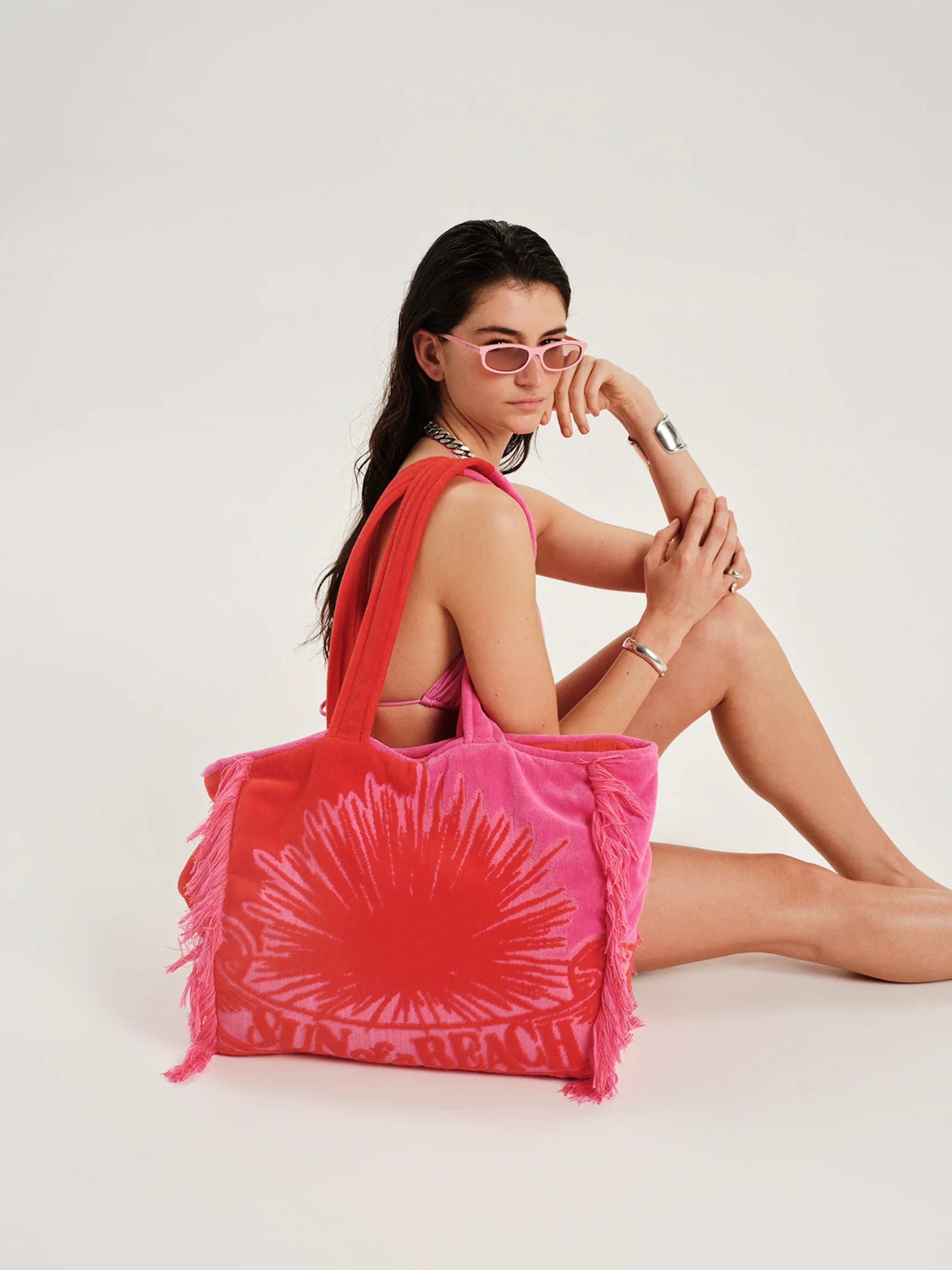 Woman holding a pink tie-dye bag on a white background