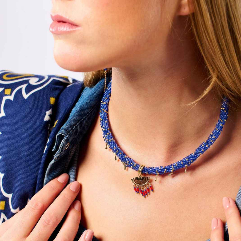 Close-up of a person wearing a blue beaded necklace with a pendant.