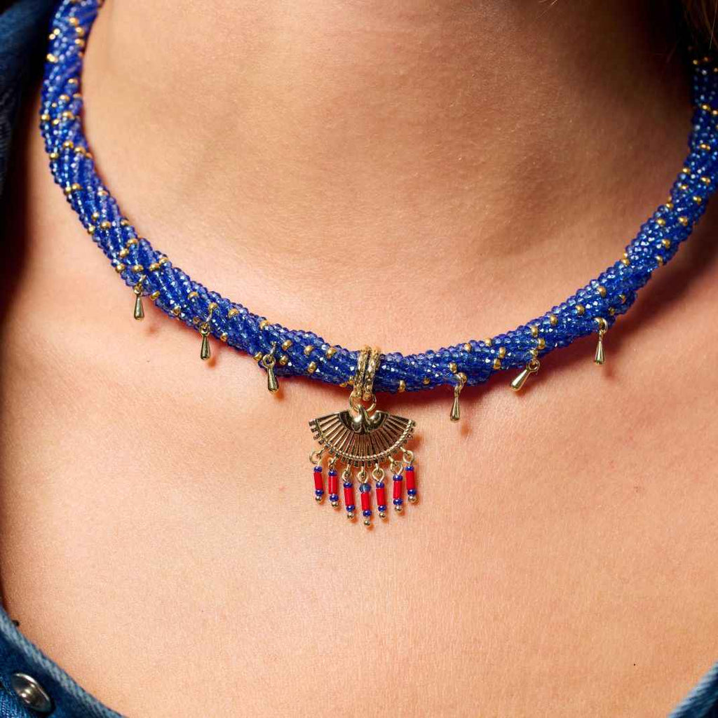 Close-up of a blue beaded necklace with a decorative pendant on a person's neck.