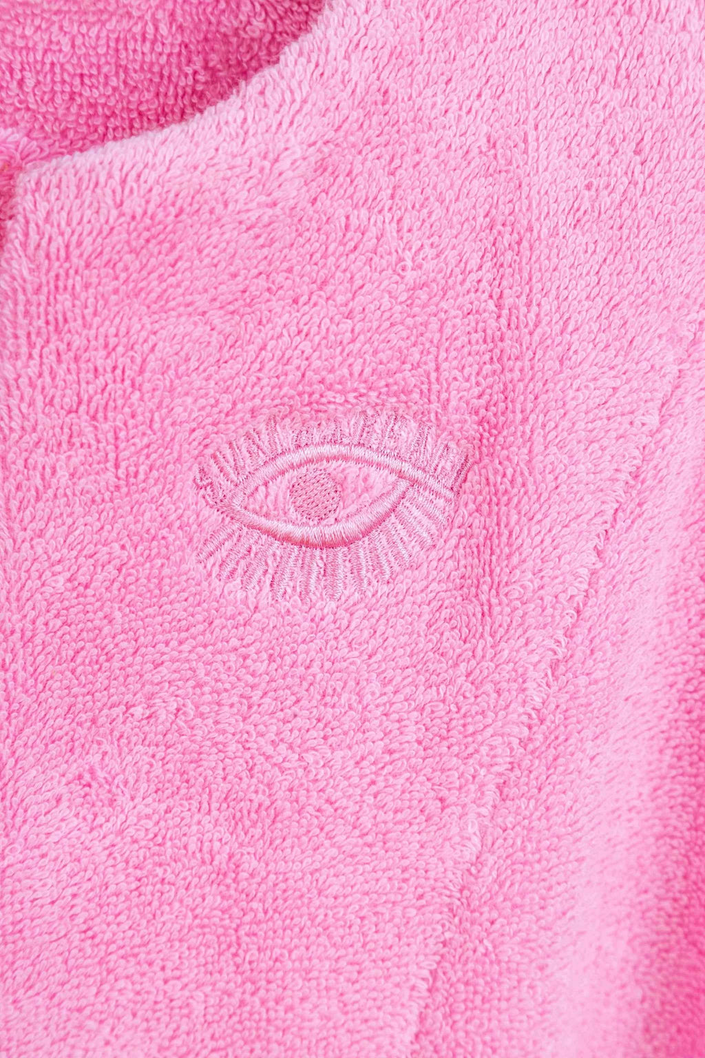 Close-up of pink fabric with an embroidered eye design