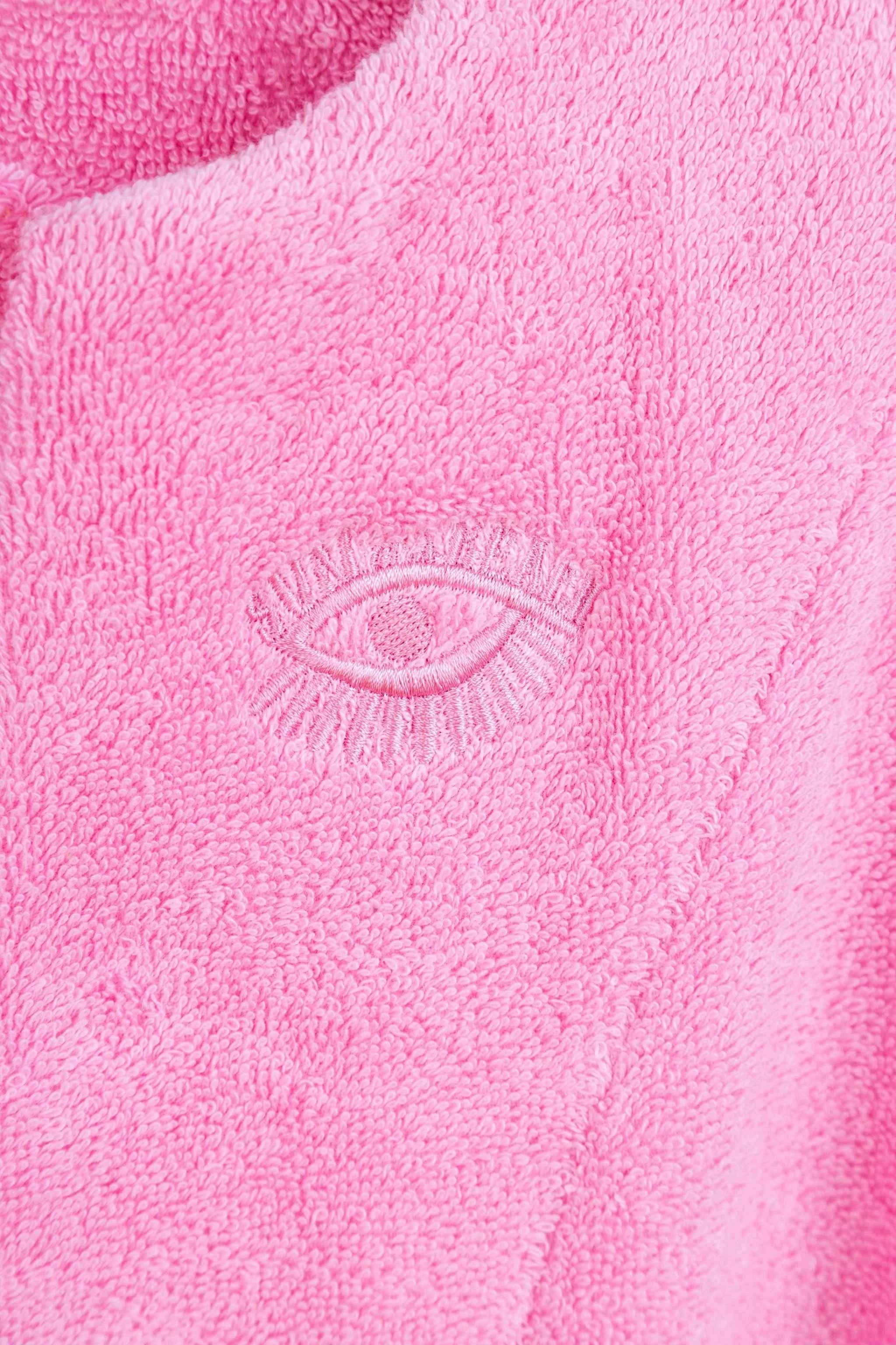 Close-up of pink fabric with an embroidered eye design