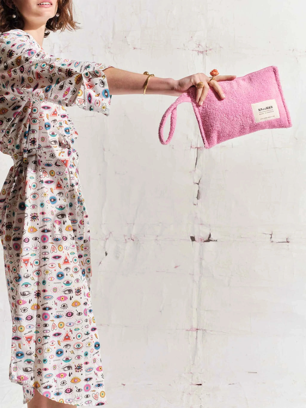 Woman holding a pink towel with a brand logo on a white couch