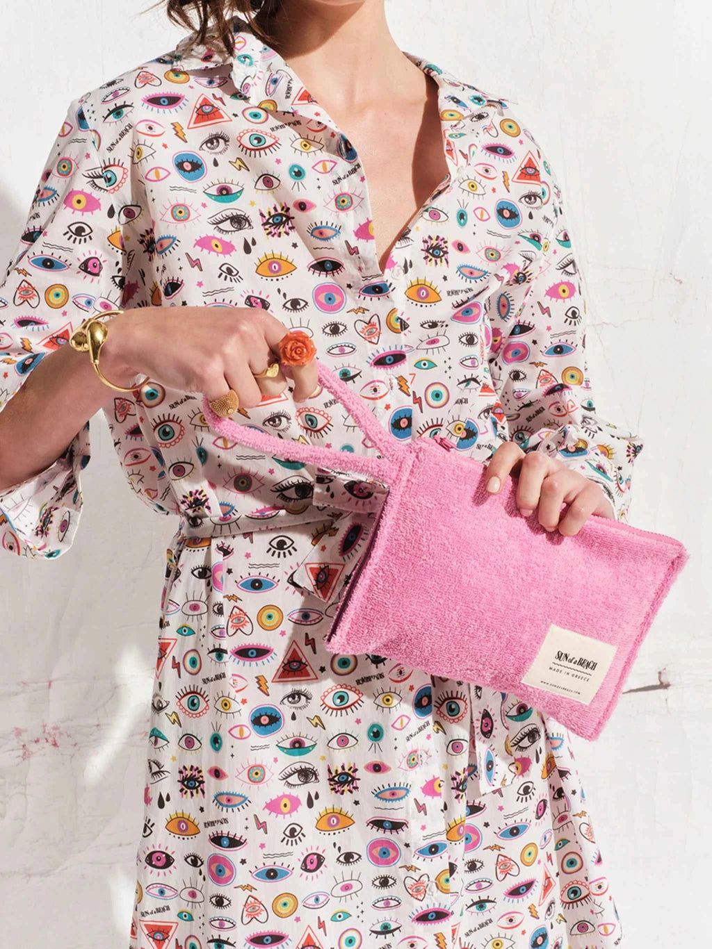 Person holding a pink pouch with a colorful patterned shirt