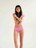 Woman wearing a pink bikini bottom on a white background