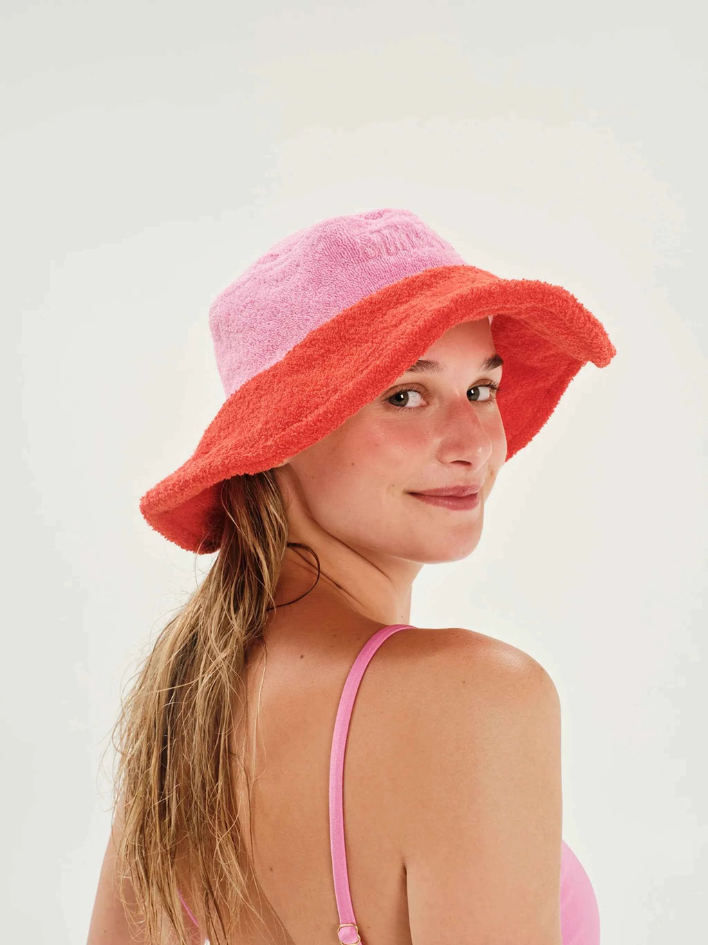 Woman wearing a pink and red bucket hat on a white background