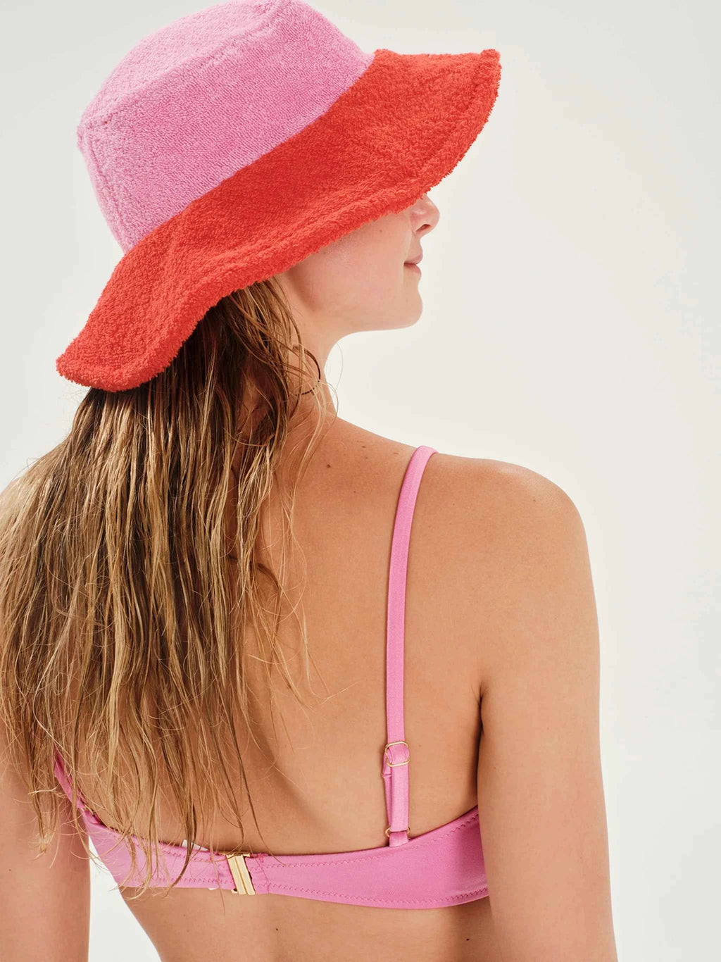 Woman wearing a pink bikini and a red and pink sun hat on a white background