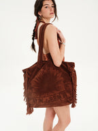 Woman wearing a brown fringe dress with a white background