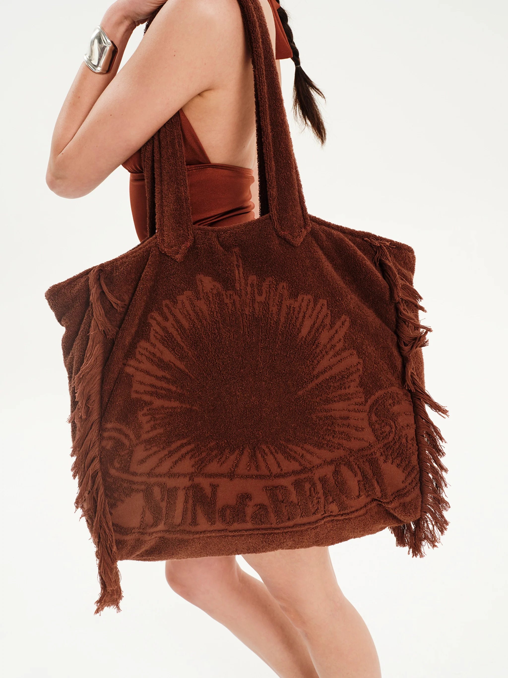 Brown tote bag with sun design and 'Blud of a Blud' branding held by a person.
