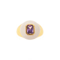 Ring with a gold band and purple gemstone on a white background