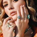 Close-up of a woman's hands wearing multiple turquoise rings with gold accents.